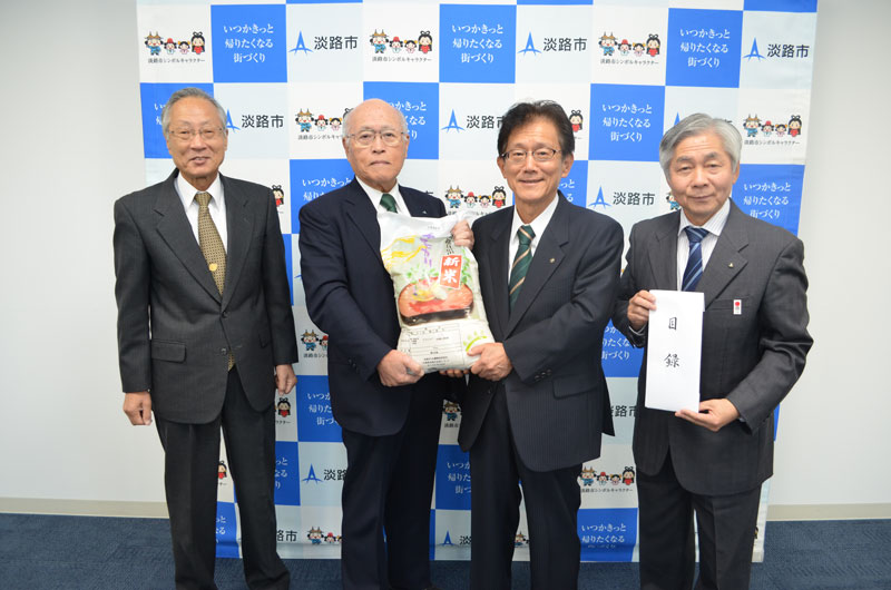 2017年11月のトピックス「「淡路島キヌヒカリ」の新米を贈る石田正組合長（左から2人目）と受け取る門市長（左から3人目）」